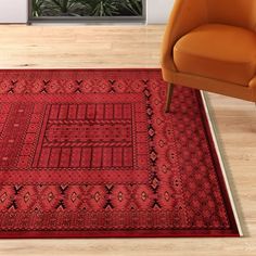 a red area rug with an orange chair in the corner and a plant behind it