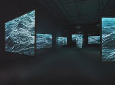 an empty room with three large screens on the wall and water in the floor, all lit up