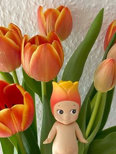 there is a small doll next to some tulips