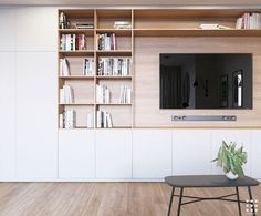 a living room with bookshelves and a television mounted on the wall next to a coffee table