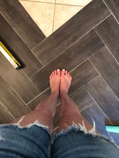 a person with ripped jeans standing in front of a tile floor