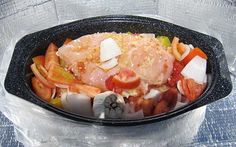 a black bowl filled with lots of food on top of a plastic tablecloth covered surface