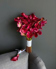 a bouquet of red flowers sitting on top of a gray couch next to a wall