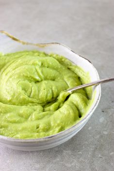 a bowl filled with green guacamole on top of a table