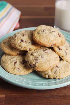 chocolate chip cookies on a blue plate with a glass of milk next to it,