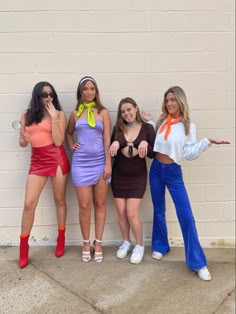 four girls are posing in front of a brick wall