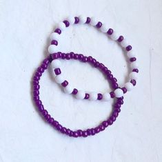 two purple and white beaded bracelets sitting next to each other