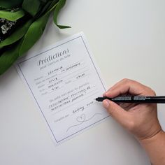 a person holding a pen over a piece of paper that has been written on it