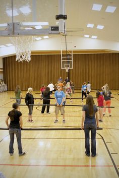 a group of people standing on top of a gym floor next to a basketball hoop