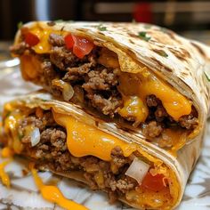 two burritos on a plate with cheese and meat