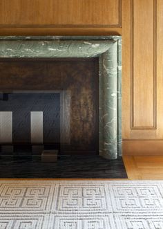 a fireplace in a room with wood paneling on the walls and carpeted floor