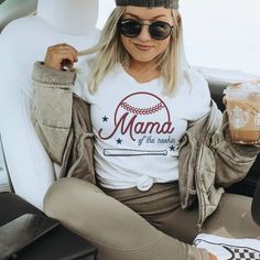 a woman sitting in the back seat of a car holding a drink and wearing a baseball cap