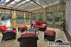 a sun room with red couches and chairs on the wooden floored patio area