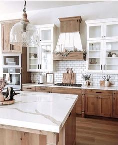 a kitchen with wooden cabinets and white marble counter tops, an island in the middle