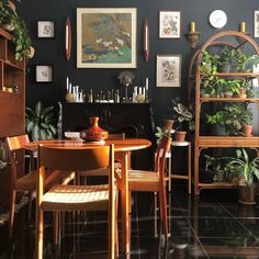 a dining room filled with lots of plants and pictures hanging on the wall above it