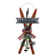 a merry christmas sign hanging from the side of a pole with bells and wreaths