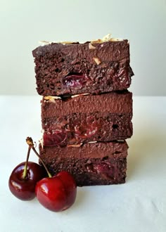 three pieces of chocolate cake with cherries on the side