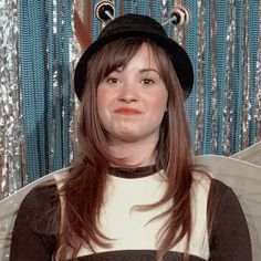 a woman with long brown hair wearing a black and white shirt, hat and angel wings