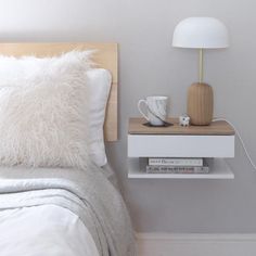 a bed with white pillows and a wooden headboard next to a lamp on a nightstand