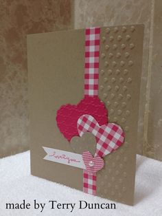 a card made by tery duncan with heart and ribbon on it, sitting on a white surface