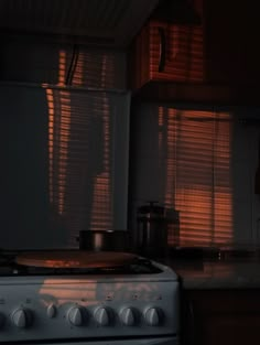 a stove top oven sitting inside of a kitchen next to a window covered in blinds