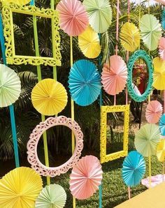 colorful paper umbrellas are hanging on the wall in front of a table with chairs