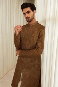 Coffee sherwani with all-over gold sequin and tonal thread embroidery. Comes with ivory straight pants.
Component: 2
Pattern: Embroidery
Type Of Work: Thread and Sequin
Neckline: Mandarin Collar
Sleeve Type: Full
Fabric: Georgette
Color: Brown,Gold
Other Details: 
Welt pocket in front
Sherwani with side slits
Note: Inner kurta worn by the model is not for sale
Occasion: Wedding - Aza Fashions Sawan Gandhi, Types Of Work, Luxury Sale, Pattern Embroidery, Thread Embroidery, Gold Thread, Buy Gold, Gold Sequin, Straight Pants