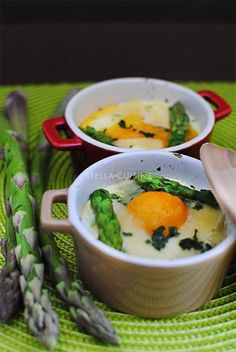 two bowls filled with eggs and asparagus on top of a green place mat