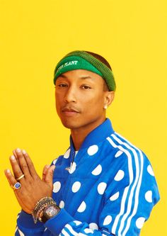 a man in blue shirt and white polka dot headband standing with his hands together