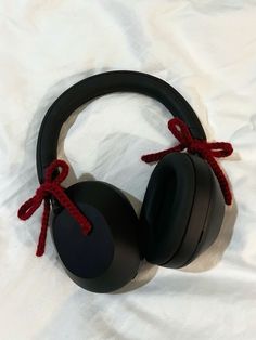 a pair of black headphones with red cord on white sheeted bedding, top view