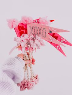 a person holding up a pink sign with flowers and ribbons attached to it's sides