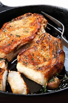 two pieces of meat are being cooked in a skillet with mushrooms and herbs on the side