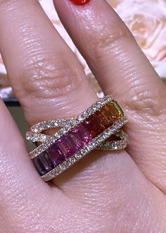 a close up of a person's hand with two rings on their fingers and an orange flower in the background