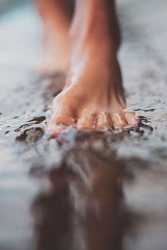 a person walking in the water with their bare feet