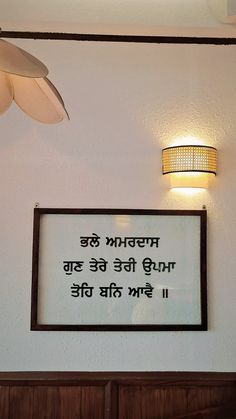 a sign hanging on the side of a white wall next to a lamp and light fixture