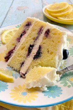 a slice of cake on a plate with blueberries and lemons next to it