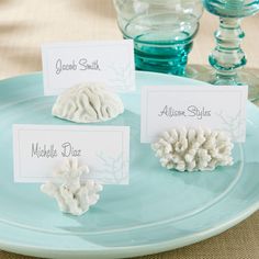 three place cards on a plate with sea shells and seashells in the background