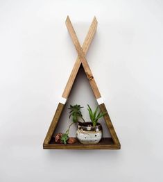 a triangle shaped shelf with plants in it and two wooden sticks sticking out of the top