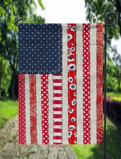 an american flag quilt hanging on a clothes line in the grass with trees behind it