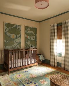 a baby's room with two paintings on the wall and a crib in the corner