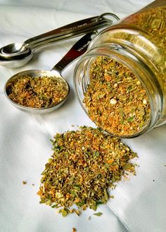 a jar filled with spices next to two spoons on top of a white cloth