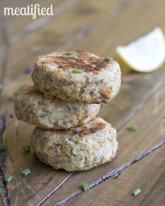 three crab cakes stacked on top of each other with a slice of lemon in the background