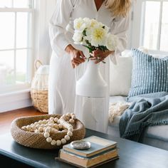 a woman arranging flowers in a vase on a coffee table