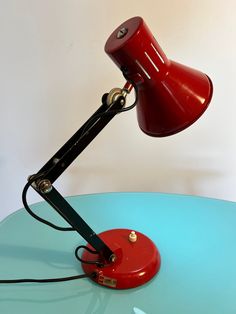 a red desk lamp sitting on top of a blue table