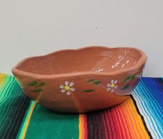 a brown bowl sitting on top of a colorful table cloth