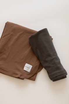 two pairs of brown and black pants laying next to each other on a white surface