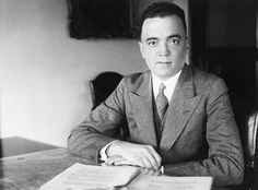 an old photo of a man sitting at a table with papers in front of him