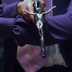 a person wearing a purple shirt holding a cross in their hands with the other hand