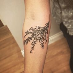 a woman's leg with a tattoo on it that has flowers and leaves growing out of it