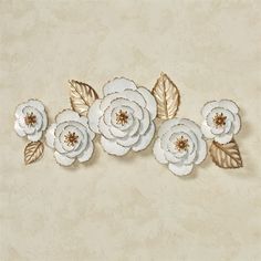 three white flowers with gold leaves on a beige wallpapered background that looks like it has been made out of paper